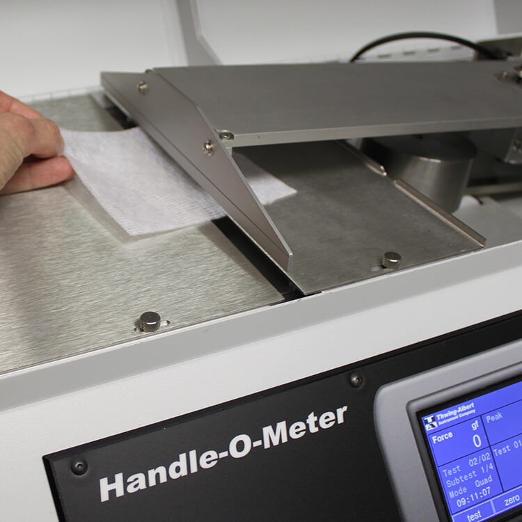 Nonwoven sample being placed on the Handle-O-Meter for softness and hand feel testing